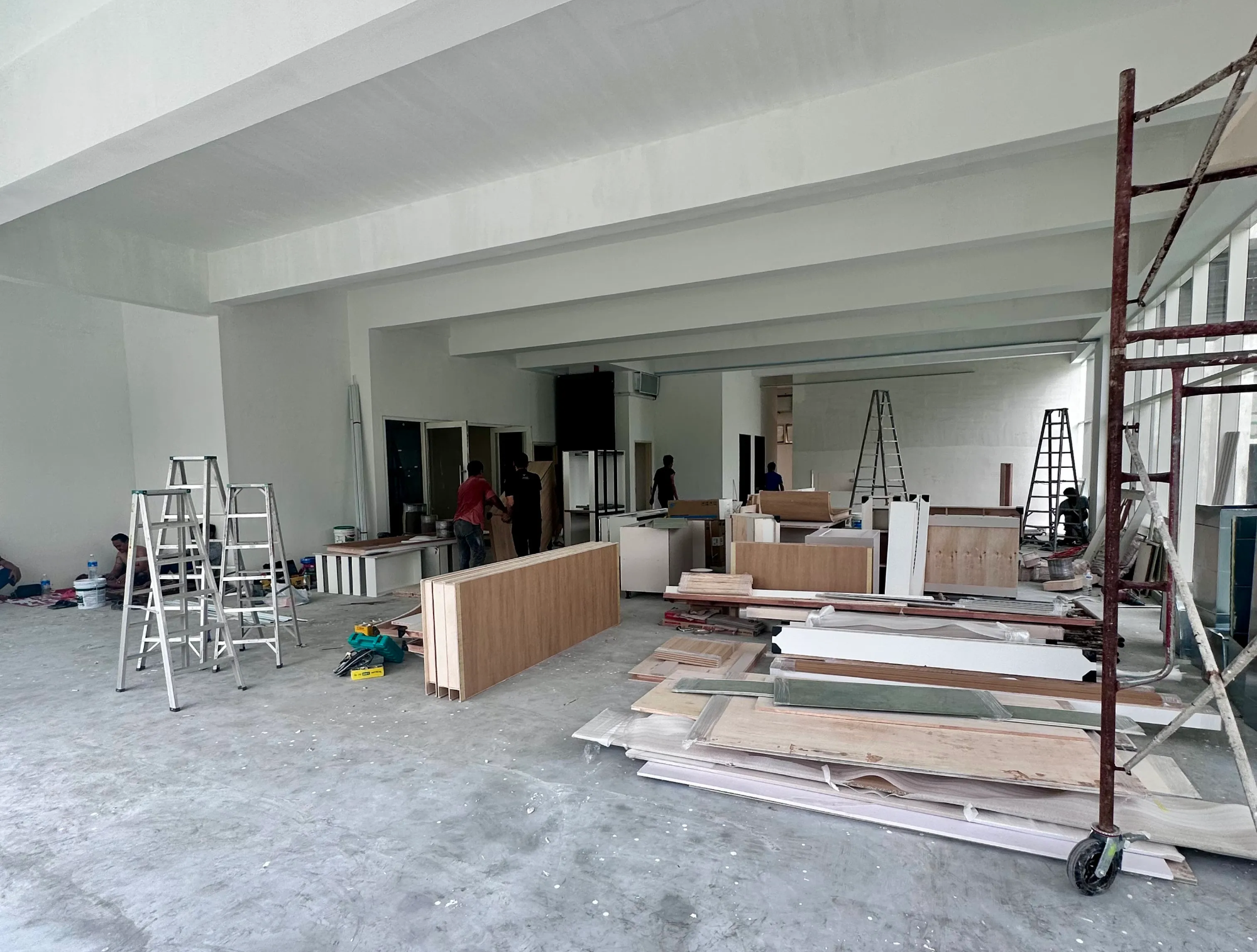 The Naru space mid-renovation — scaffolding, plywood, ladders, and a team of contractors working.