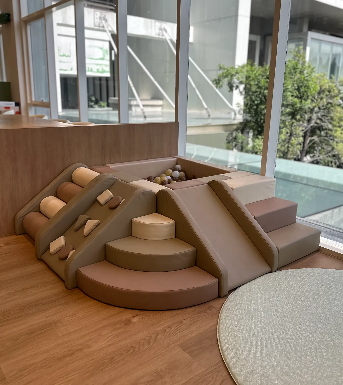The soft play structure for under-3s at Naru — tiered foam shapes in warm earth tones, with a small mini ball pit on one side.